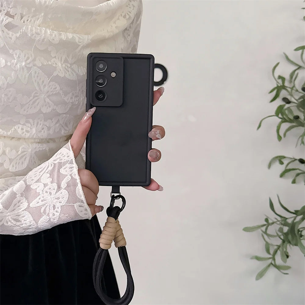 Person holding a black phone case with a lanyard on a light background